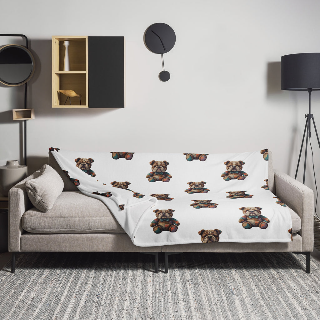 A white throw blanket featuring a repeating pattern of Boshino teddybear Bulldog illustrations, draped over a light gray sofa in a modern living room setting.