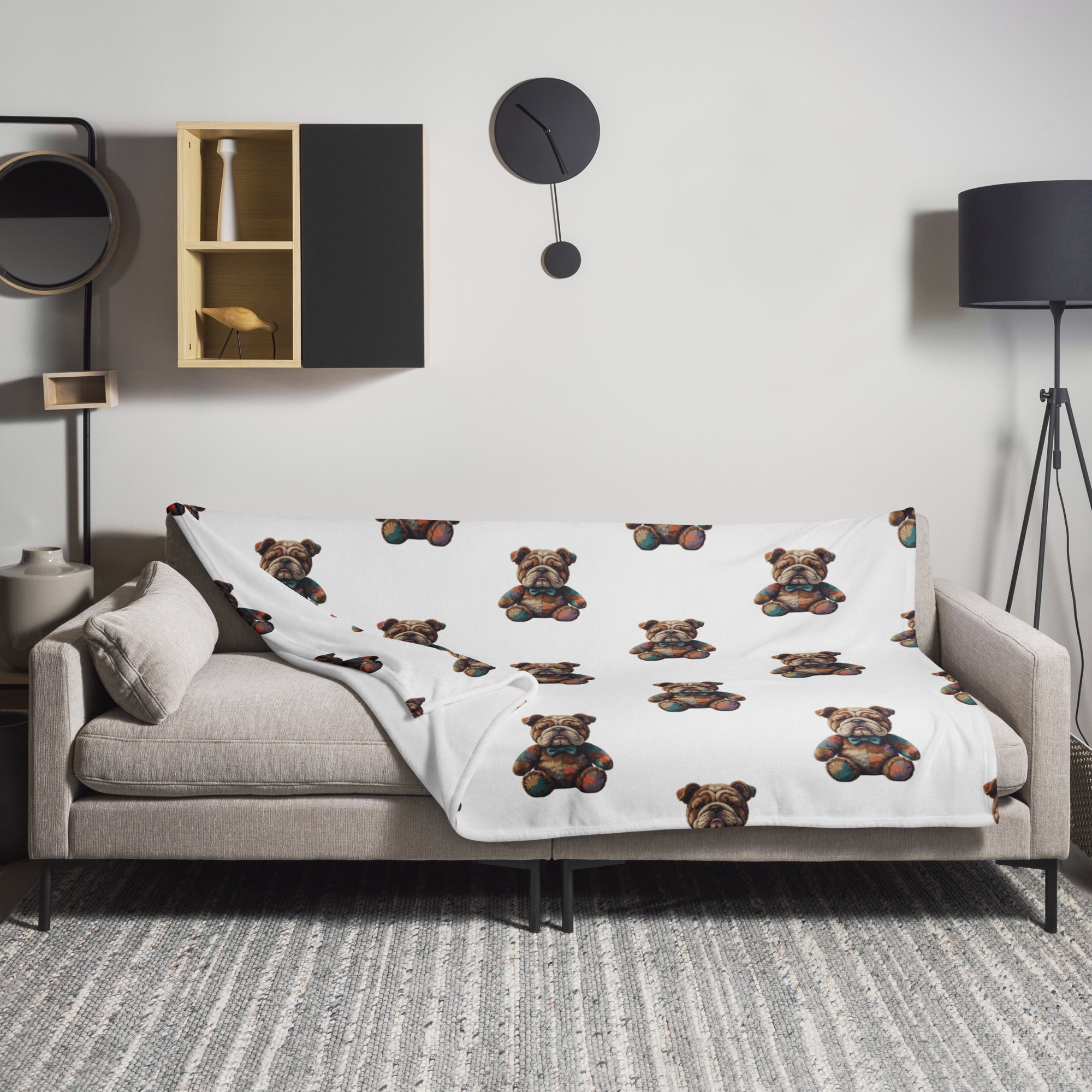 A white throw blanket featuring a repeating pattern of Boshino teddybear Bulldog illustrations, draped over a light gray sofa in a modern living room setting.